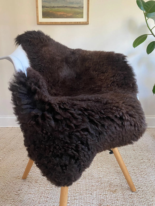 Dark Brown sheepskin rug draped over a chair 