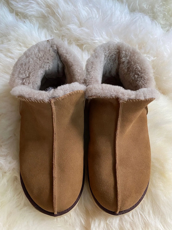 Top-view of pair of brown slippers with fluffy interior on a white fur surface