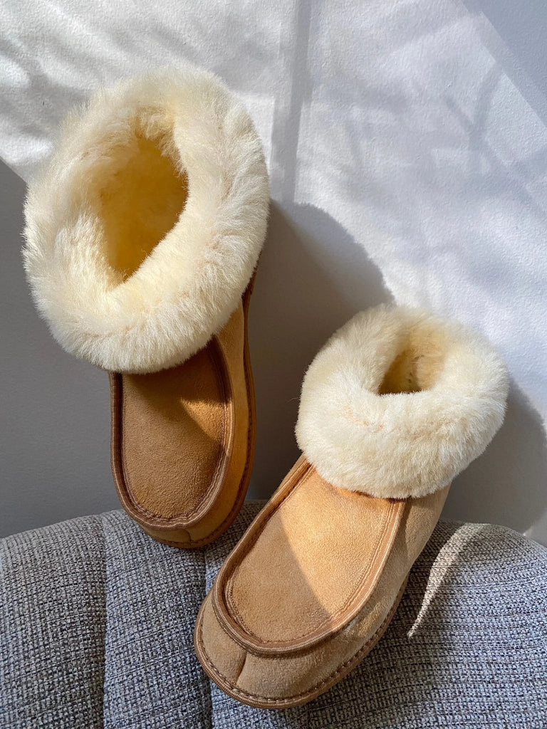 Pair of terra slipper sheepskin minimalist footwear tan on a textured surface
